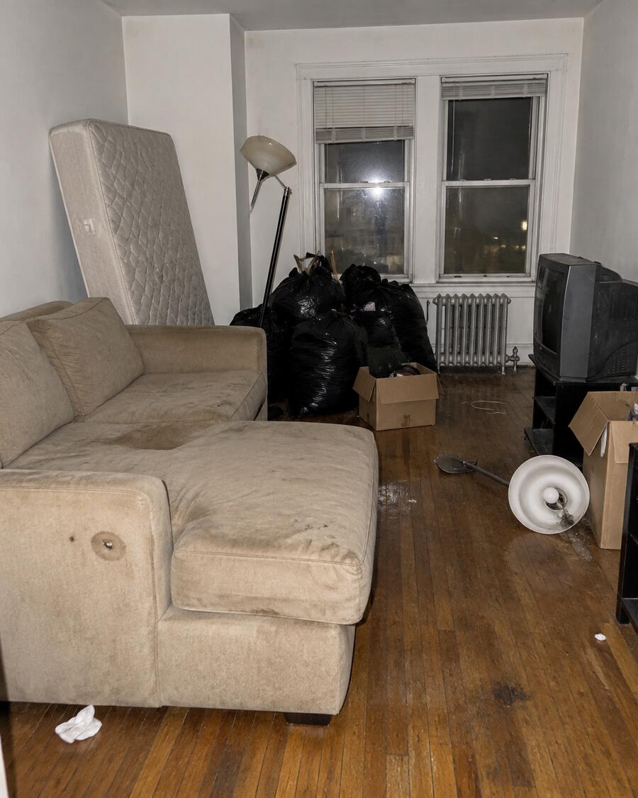 A vacated apartment full of leftover furniture and trash bags